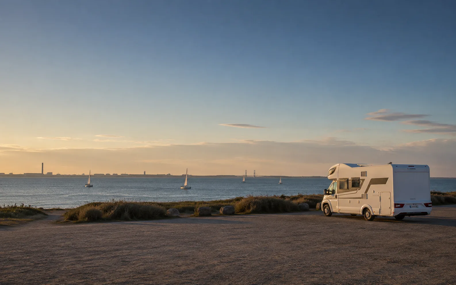 Autocaravana aparcada junto a la bahía de Cádiz con veleros al fondo