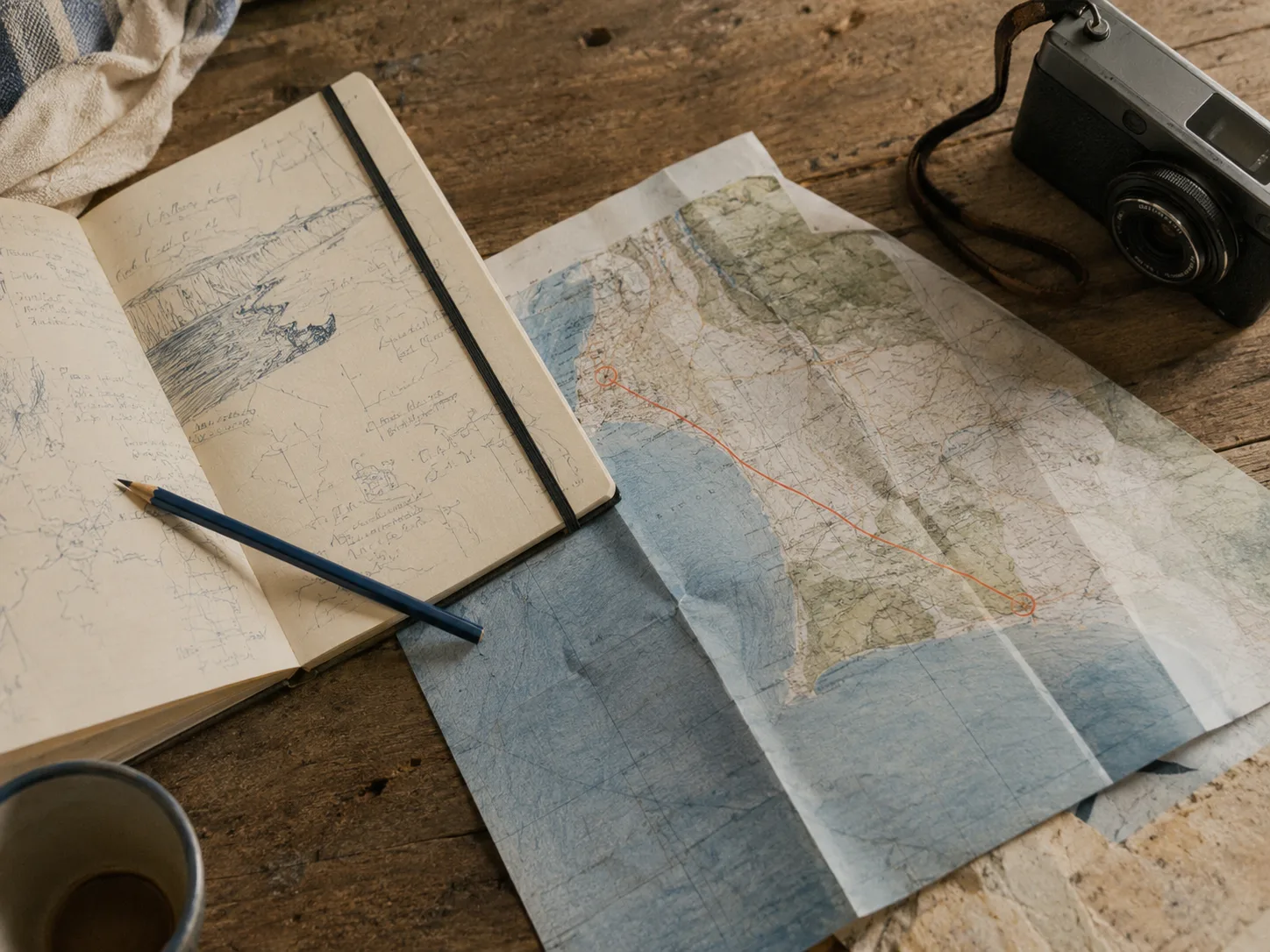 Mesa con libreta, mapa y cámara para preparar una ruta